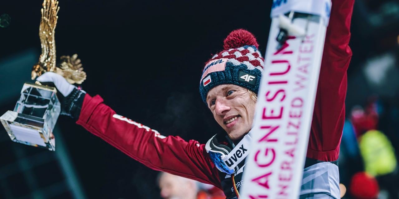 Dawid Kubacki mit dem Goldenen Adler in der rechten und den BWT Sprungski in der linken Hand.