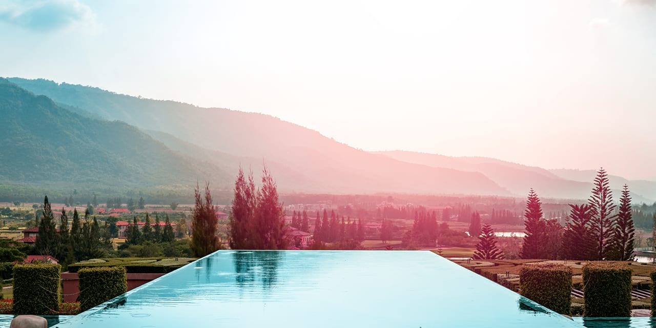 Rechteckiger Pool mit Steinplatten außenherum und drei Liegestühlen.