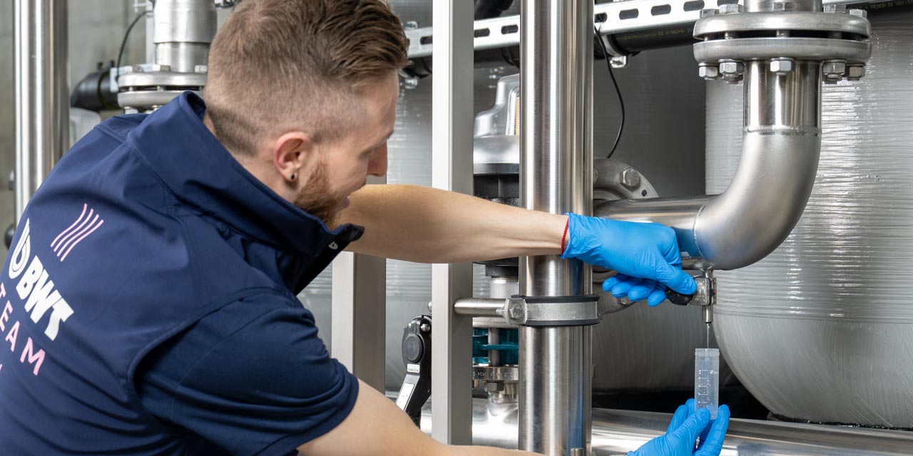 BWT Servicetechniker entnimmt eine Wasserprobe an einer industriellen Wasseranlage zur Legionellenanalyse.