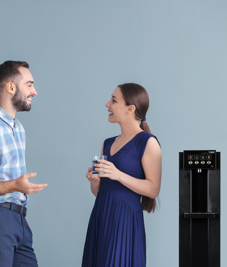 Mann und Frau stehen neben einem Wasserspender von BWT.