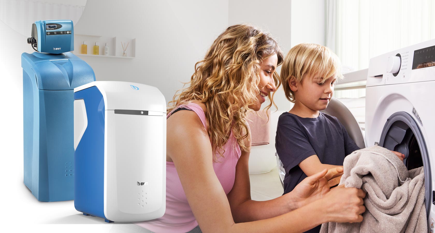 Frau und Sohn nehmen Wäsche aus Waschmaschine. Zwei Enthärtungsanlagen von BWT sind auf dem Bild platziert.