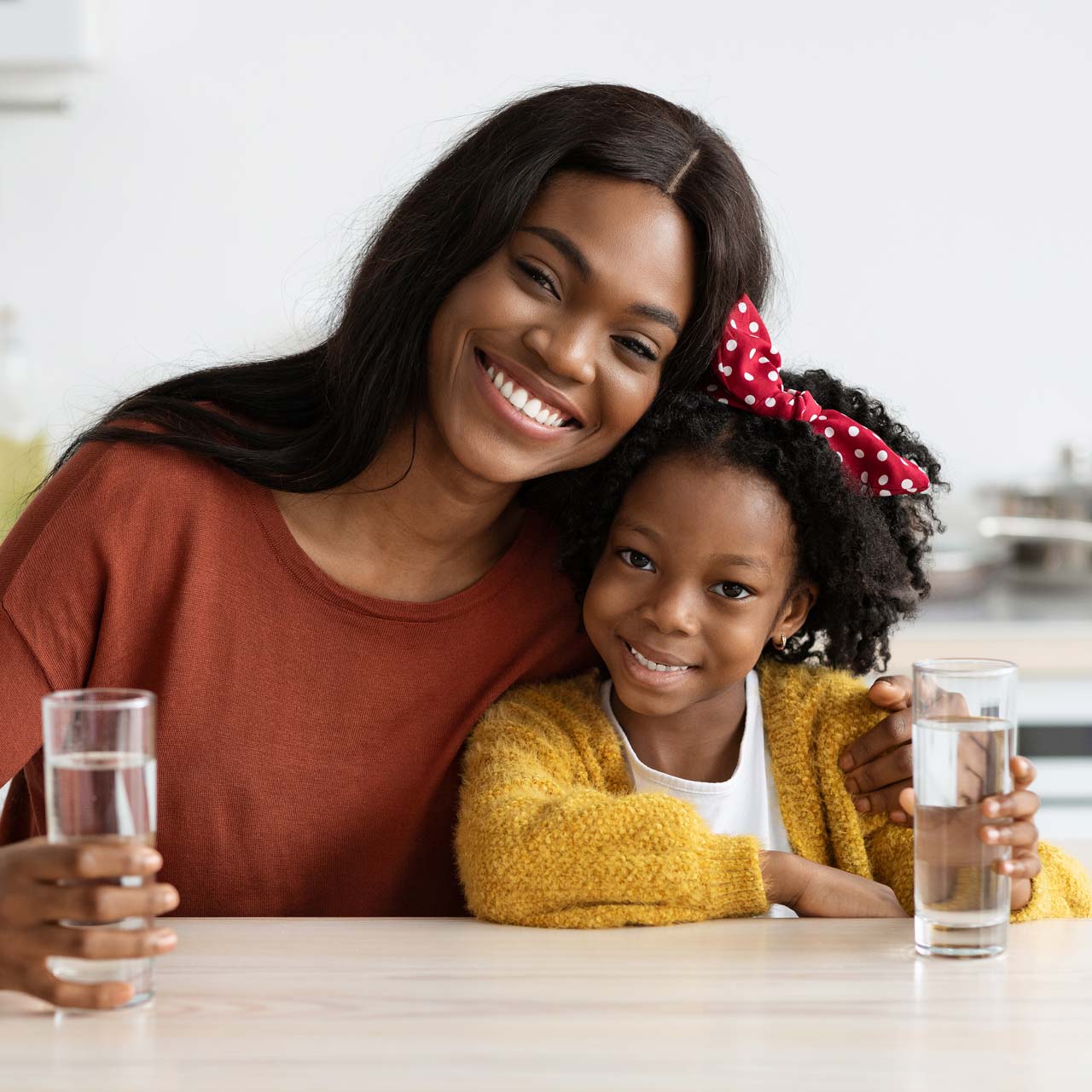 Mutter und Tochter trinken ein Glas Wasser.
