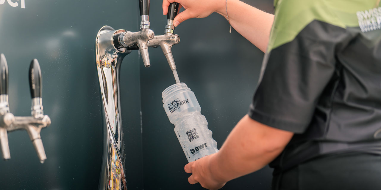 Mann bezieht Wasser an einem Wasserspender.
