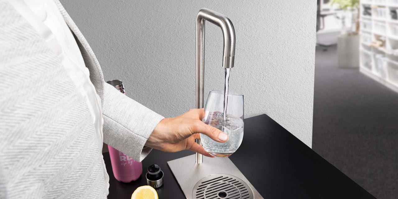 Frau hält Glas unter Wasserhahn.