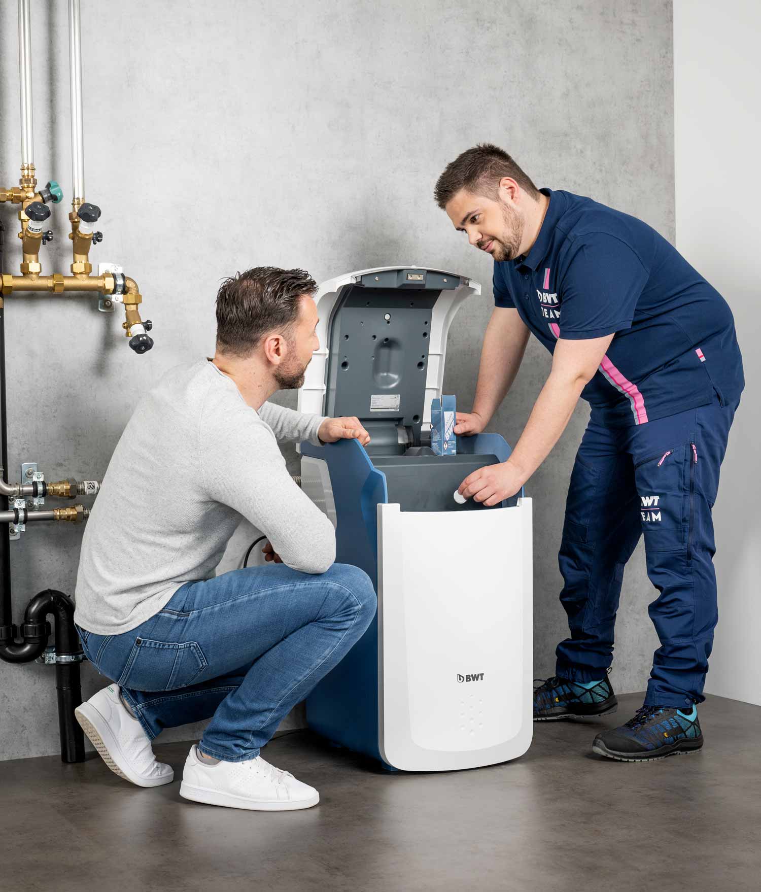 Servicetechniker steht neben Kunden und erklärt die Enthärtungsanlage.