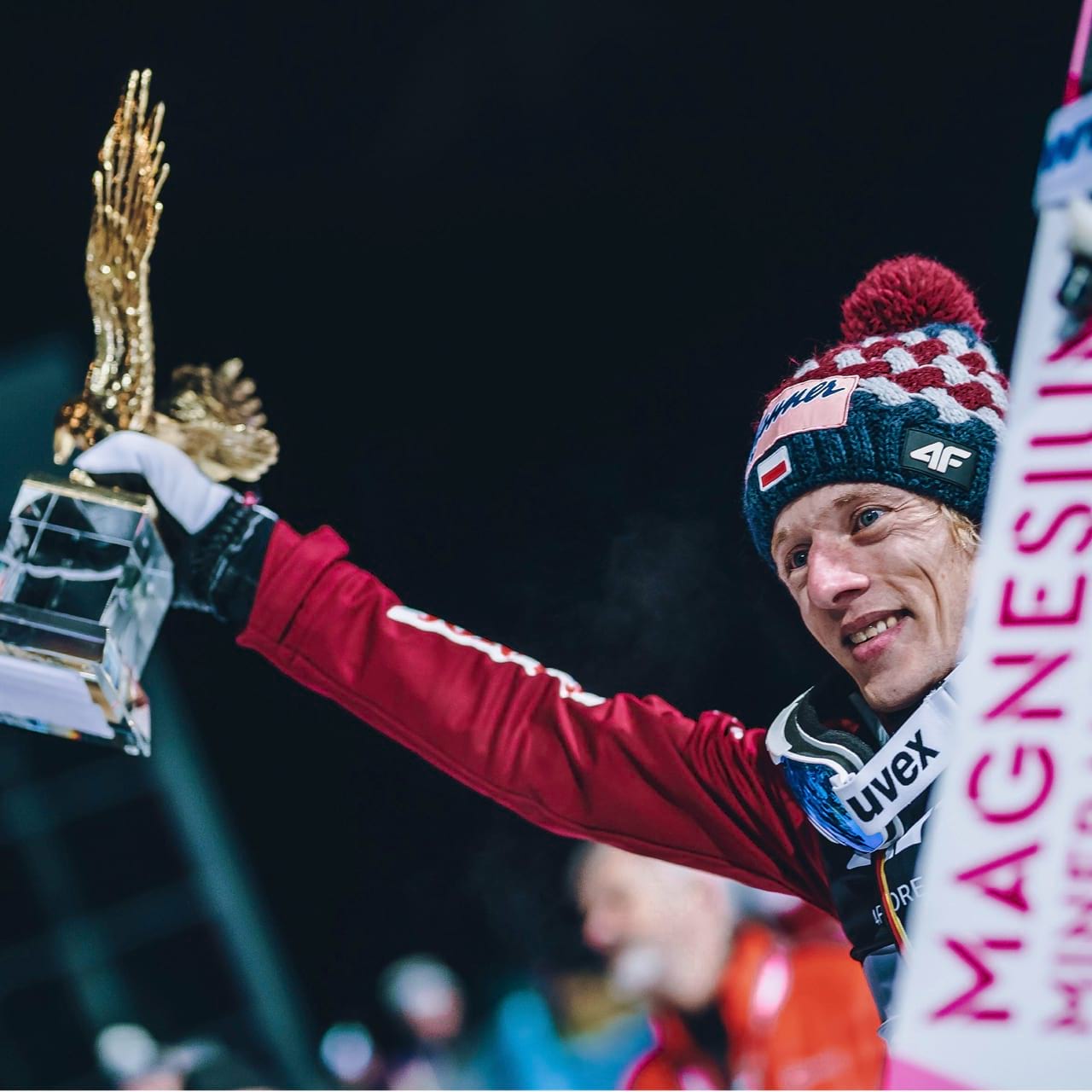 Dawid Kubacki mit dem Goldenen Adler in der rechten und den BWT Sprungski in der linken Hand.