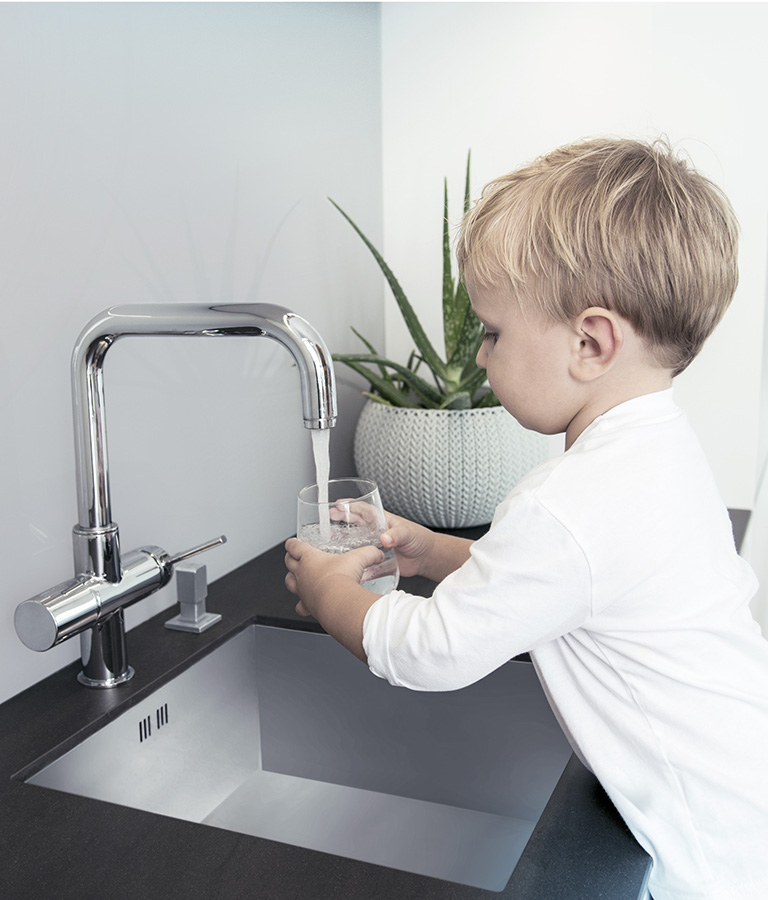 Junge füllt Wasser in Glas