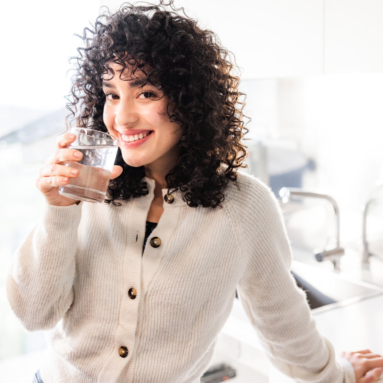Woman is smiling with a glass of water.