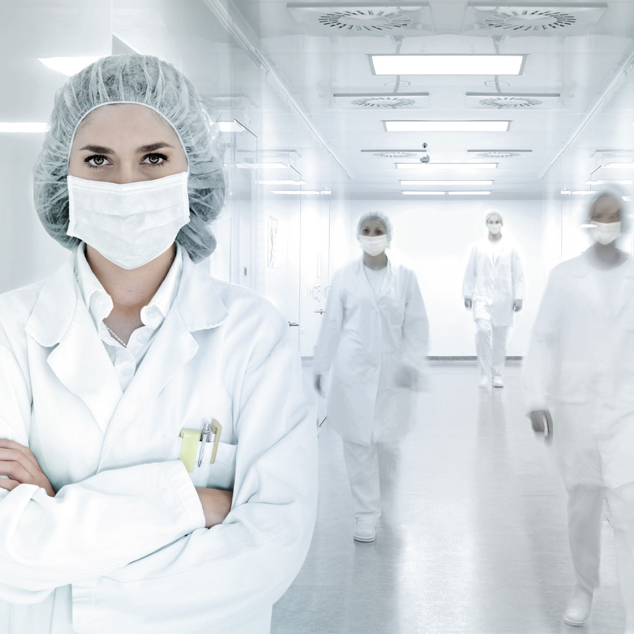 Une femme se tient dans une pièce hygiéniquement propre avec des vêtements de protection.