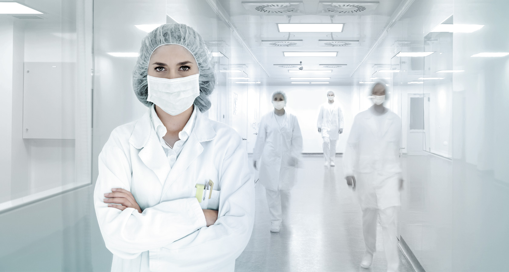 Une femme se tient dans une pièce hygiéniquement propre avec des vêtements de protection.