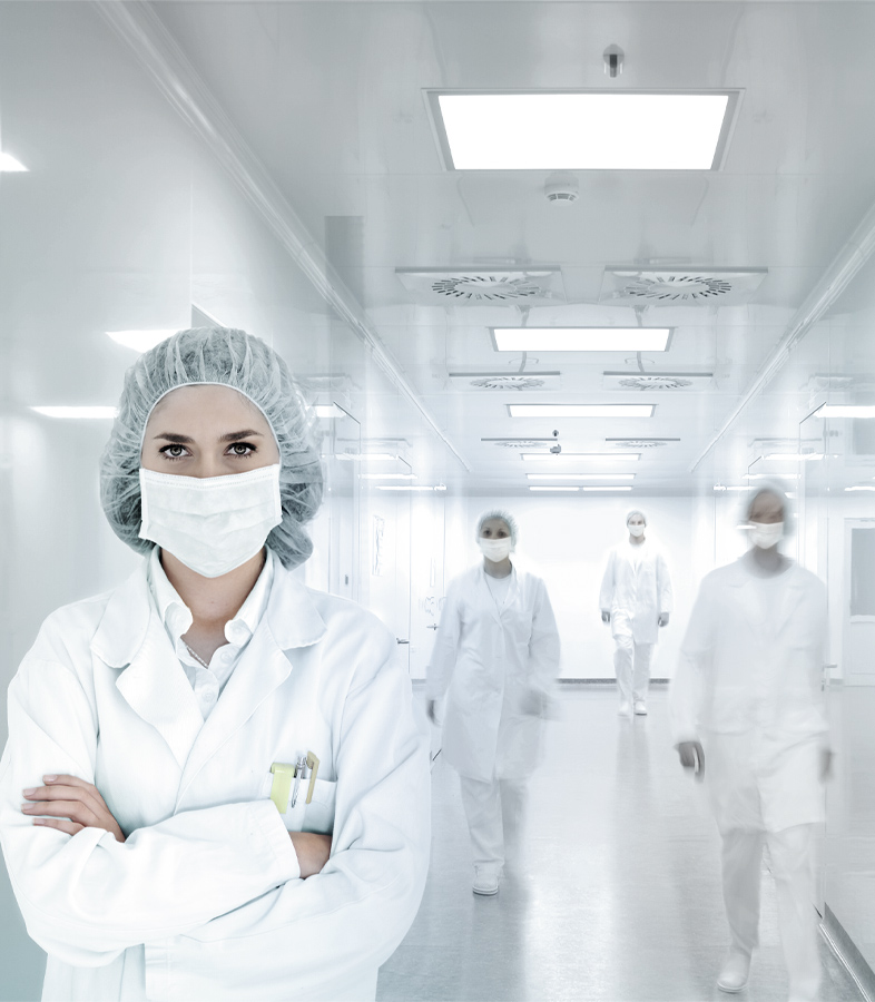 Une femme se tient dans une pièce hygiéniquement propre avec des vêtements de protection.