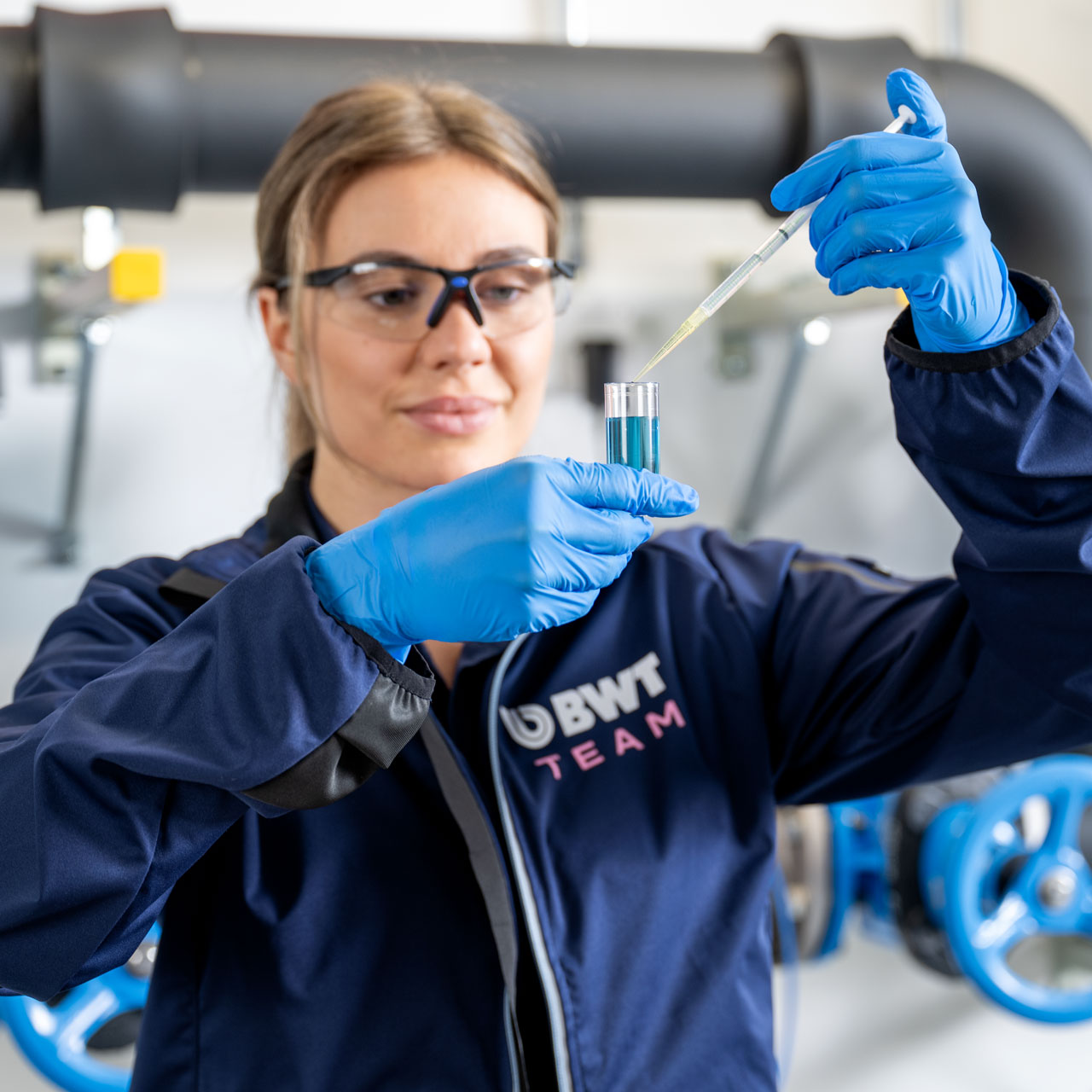 Une technicienne de service BWT prélève un échantillon d’eau sur une installation industrielle afin d’effectuer une analyse des légionelles.