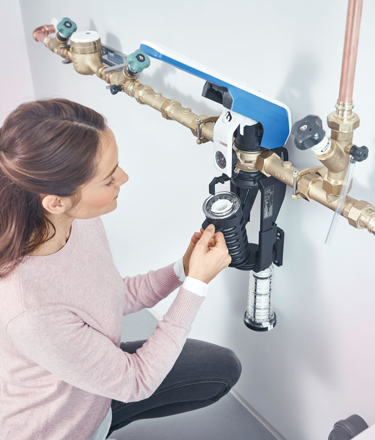 Une femme change de filtre à eau. 