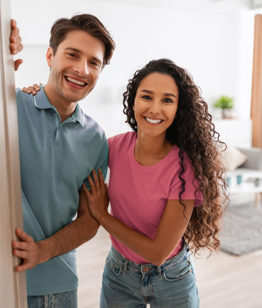 Un homme et une femme se tiennent devant la porte d'entrée.
