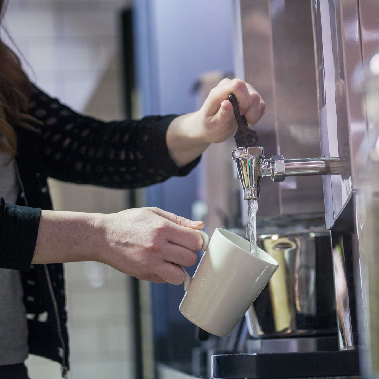Une femme se sert en eau à une fontaine.