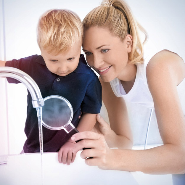 Une femme examine l'eau avec une loupe à côté d'un enfant. 
