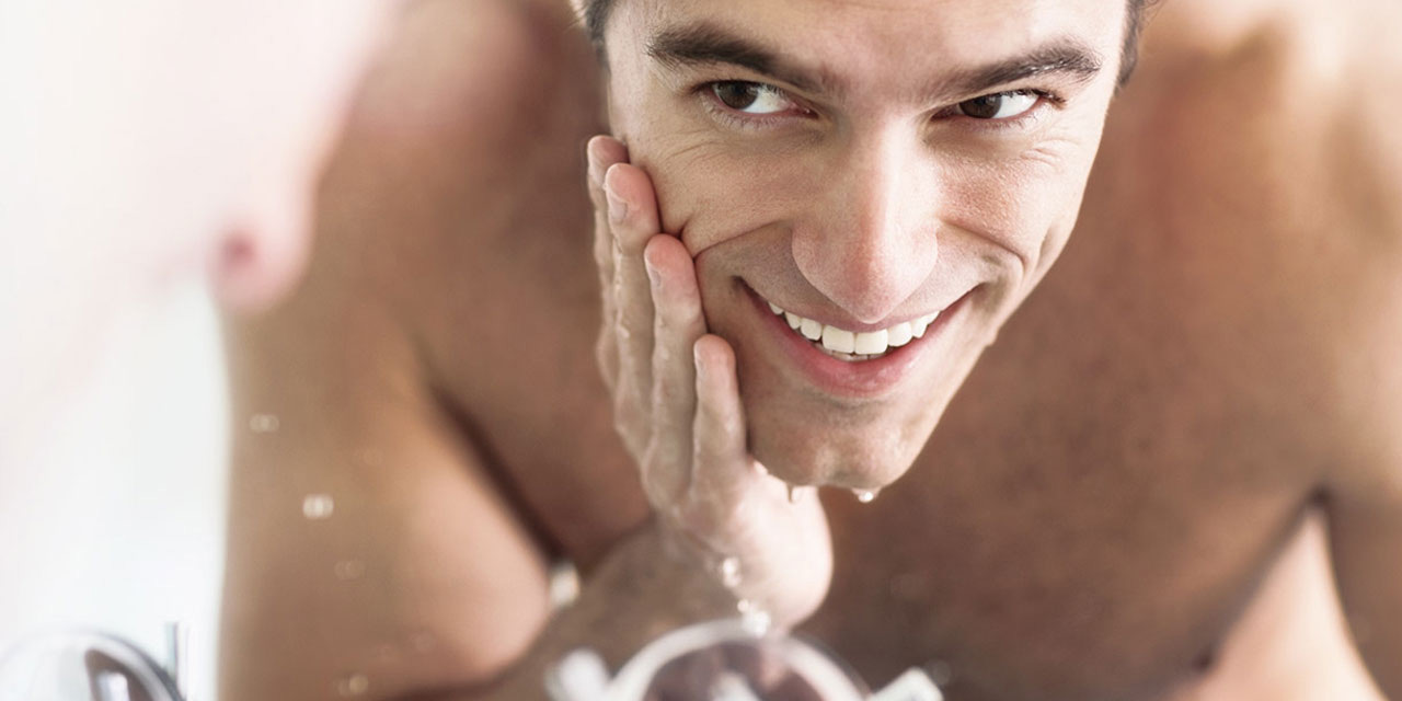 Homme souriant dans le miroir de la salle de bain