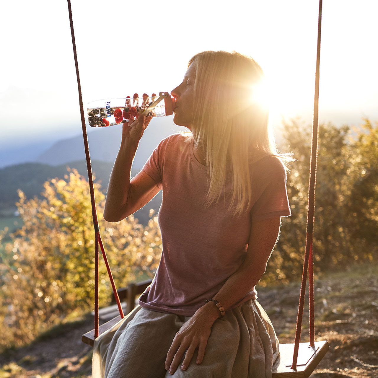 Une femme boit de l'eau sur une balançoire