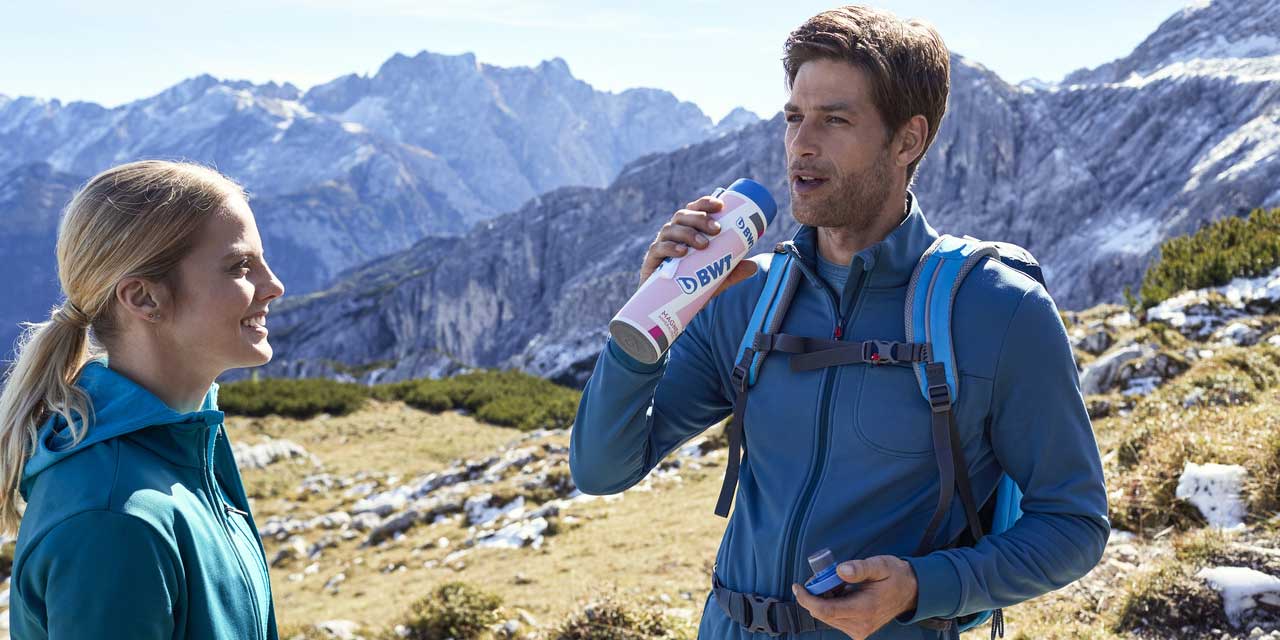 Un homme en randonnée boit de l'eau BWT