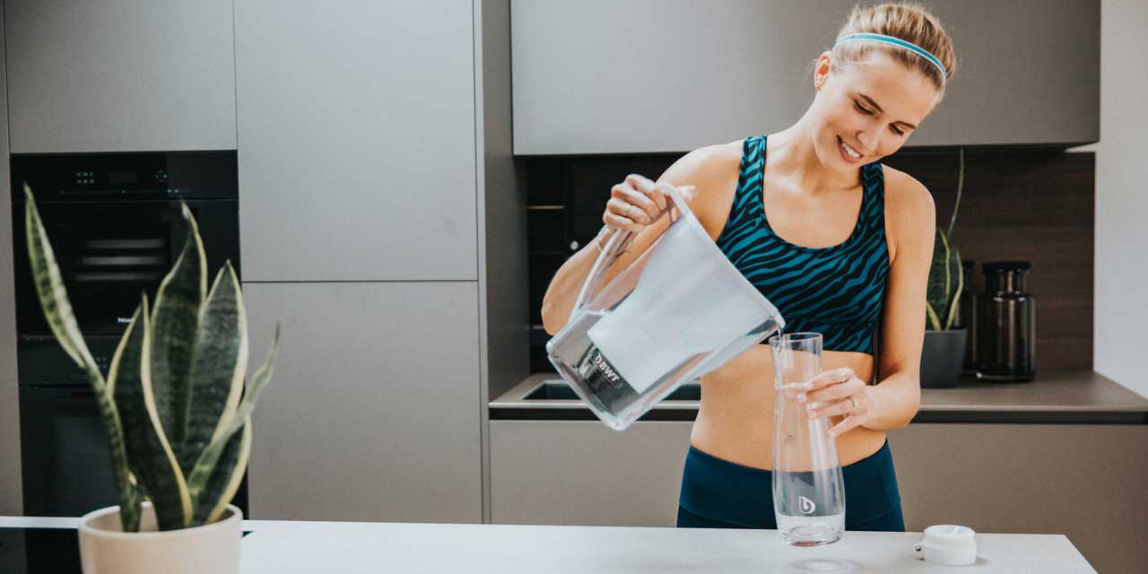 femme se sert de l'eau d'une carafe filtrante