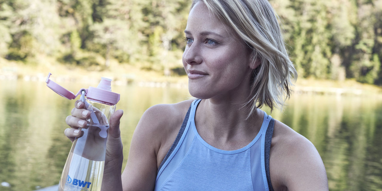 Une femme boit dans sa gourde BWT