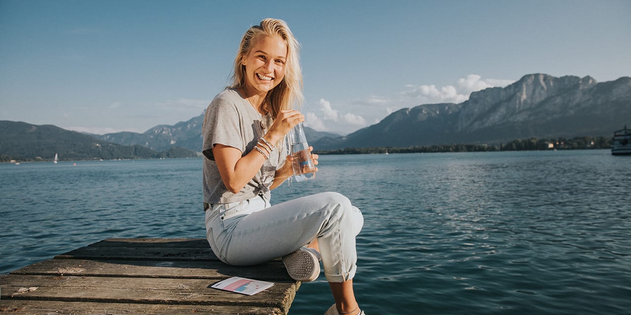 femme au bord d'un lac boit de l'eau