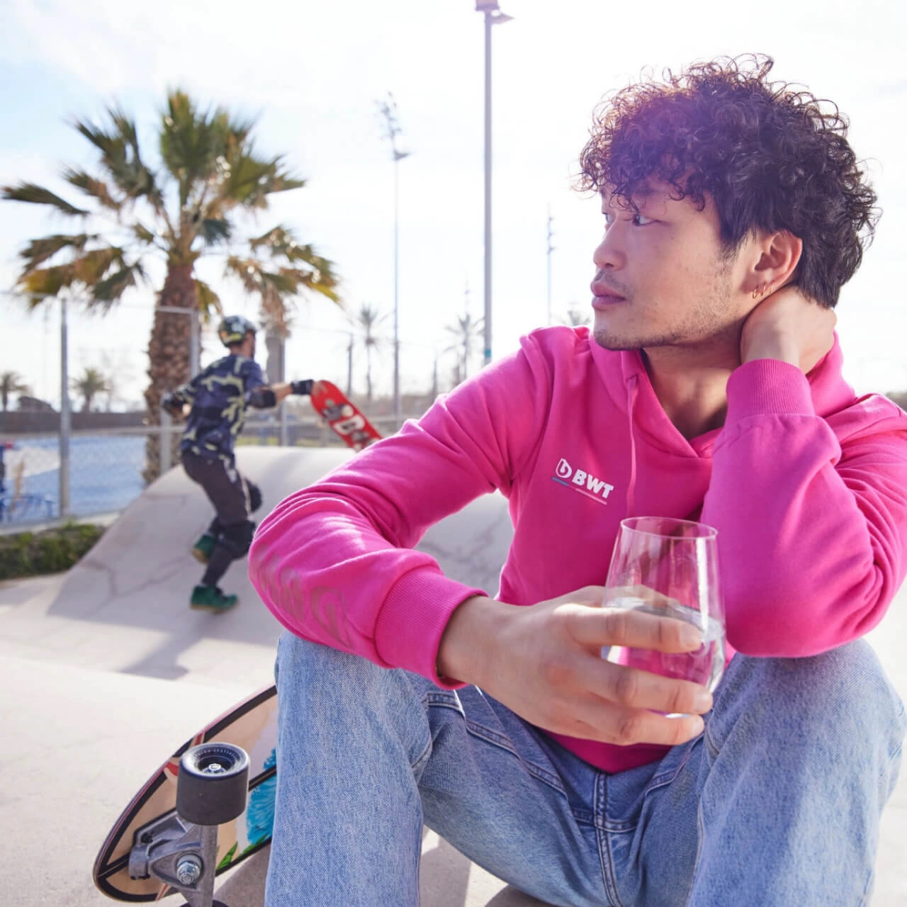 Junger Mann im Skaterpark trink Wasser aus Glas