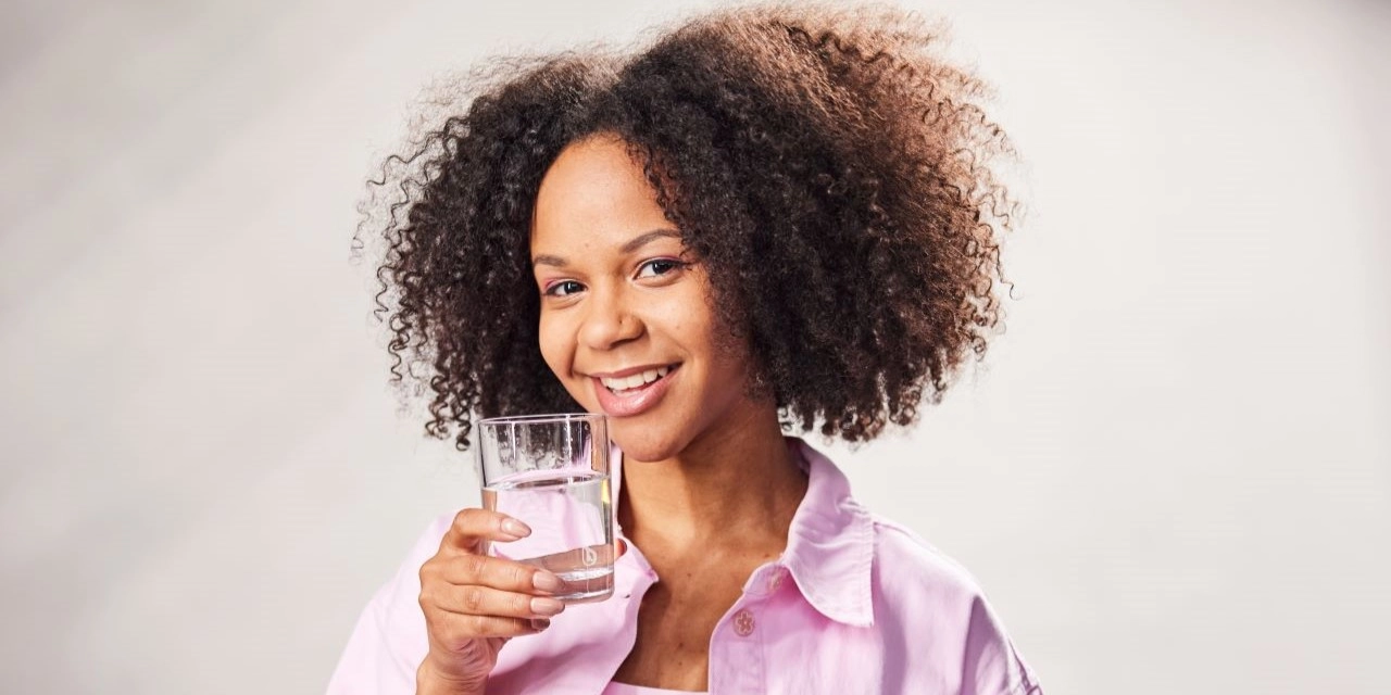 Wasser trinken Bwater Glas Lachende Frau mit Wasserglas in der Hand