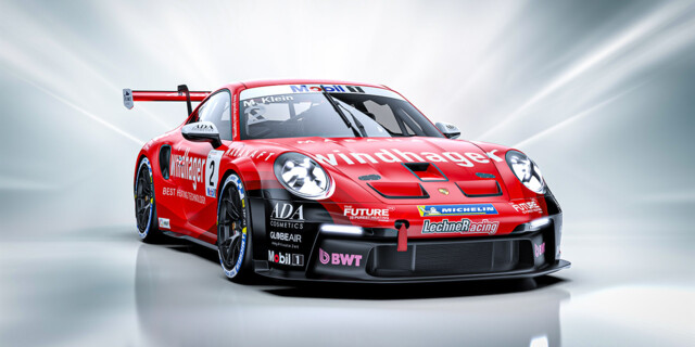 A dynamic, front-angle view of a red Porsche 911 GT3 race car featuring a Windhager logo and aerodynamic detailing.